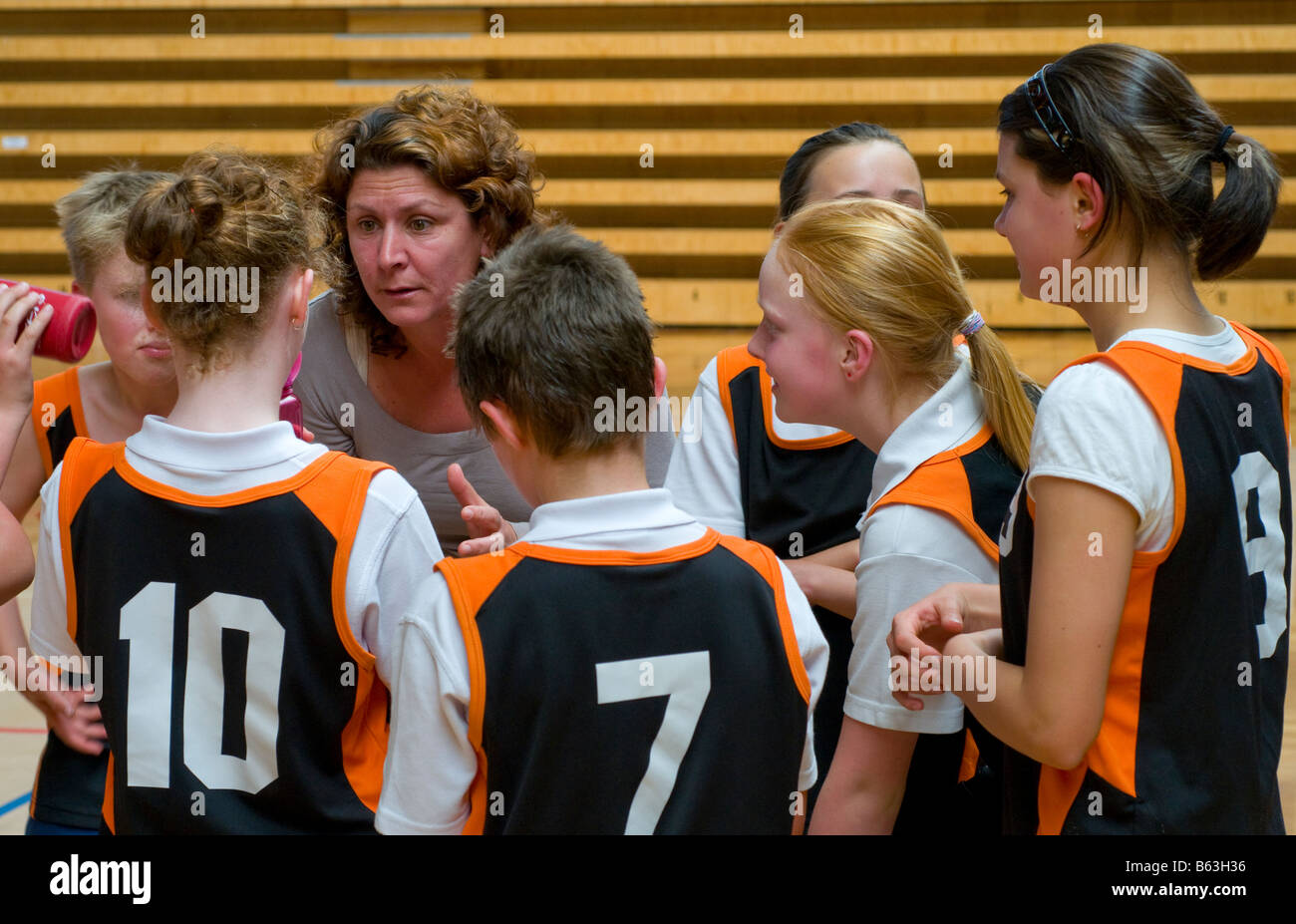 Coach discussing tactics with players of a mixed junior primary school basketball team Stock Photo