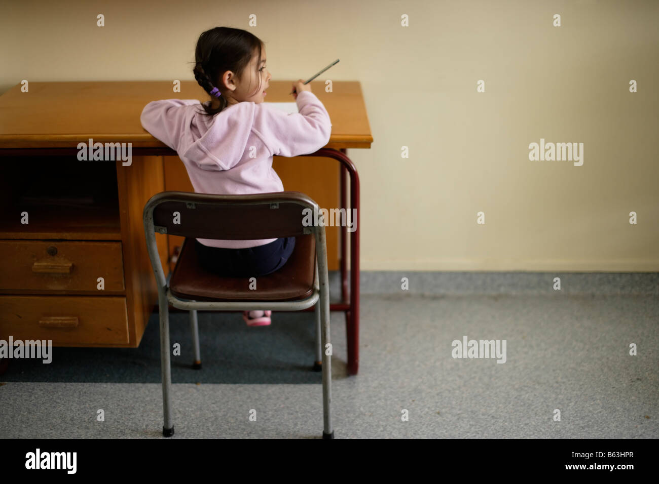 Five year old girl sitting at a desk writing Stock Photo