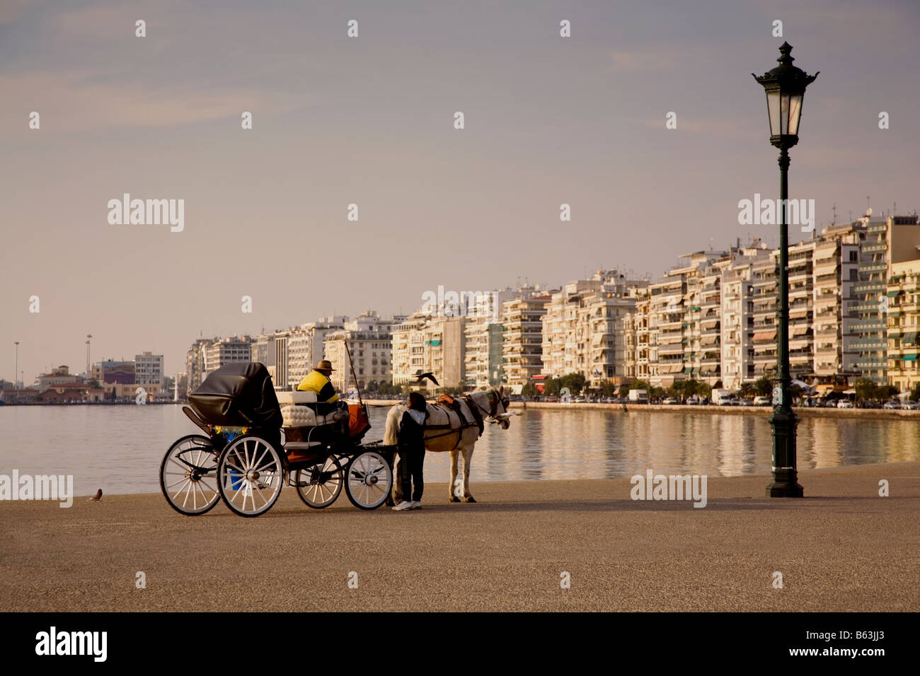 Horse cart in front of The White Tower Thessaloniki Greece Europe. Cart man talking with woman. Stock Photo