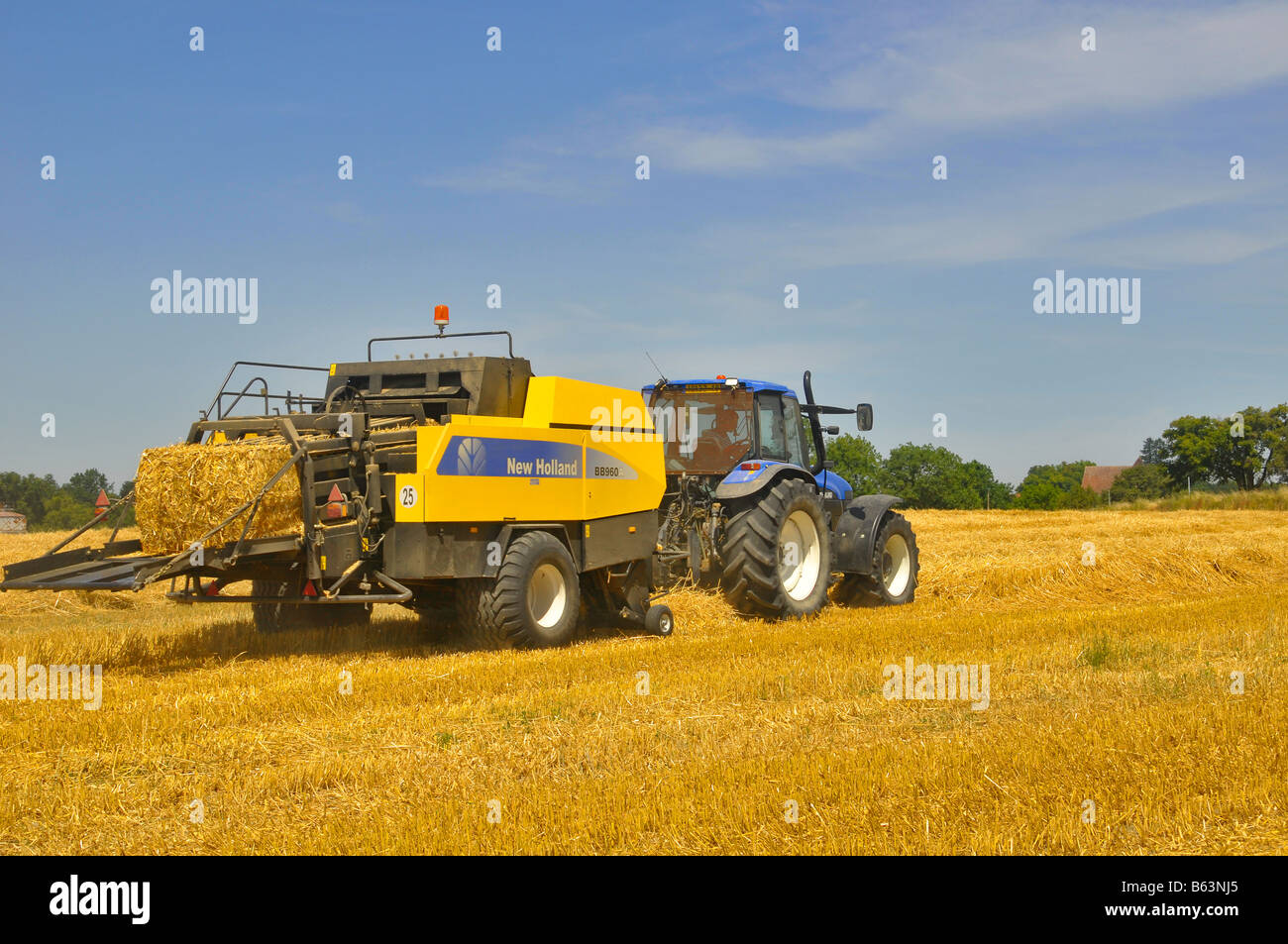Harvests: a tractor with a square baler picking straw, France. Stock Photo