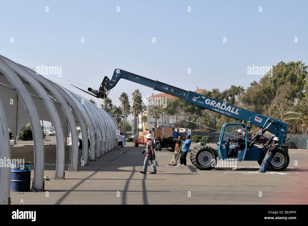 A very large tent structure is being raised at a parking lot on the