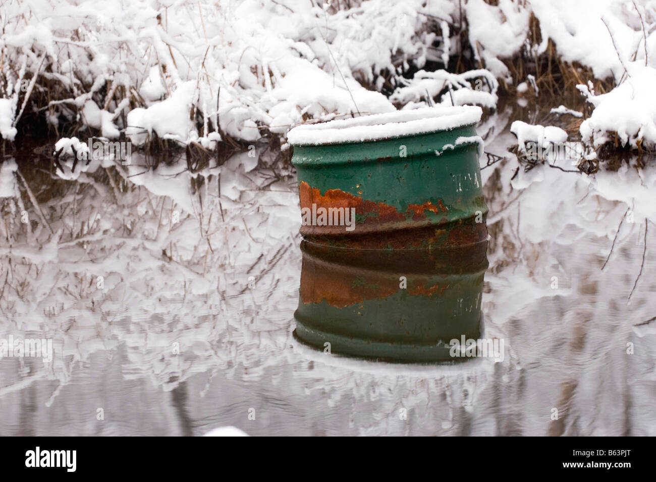 Old metal drum trash can pollutes a creek Stock Photo Alamy