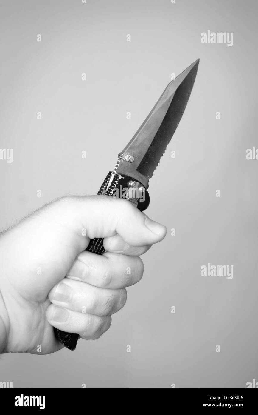 A hand gripping a scary looking knife Stock Photo