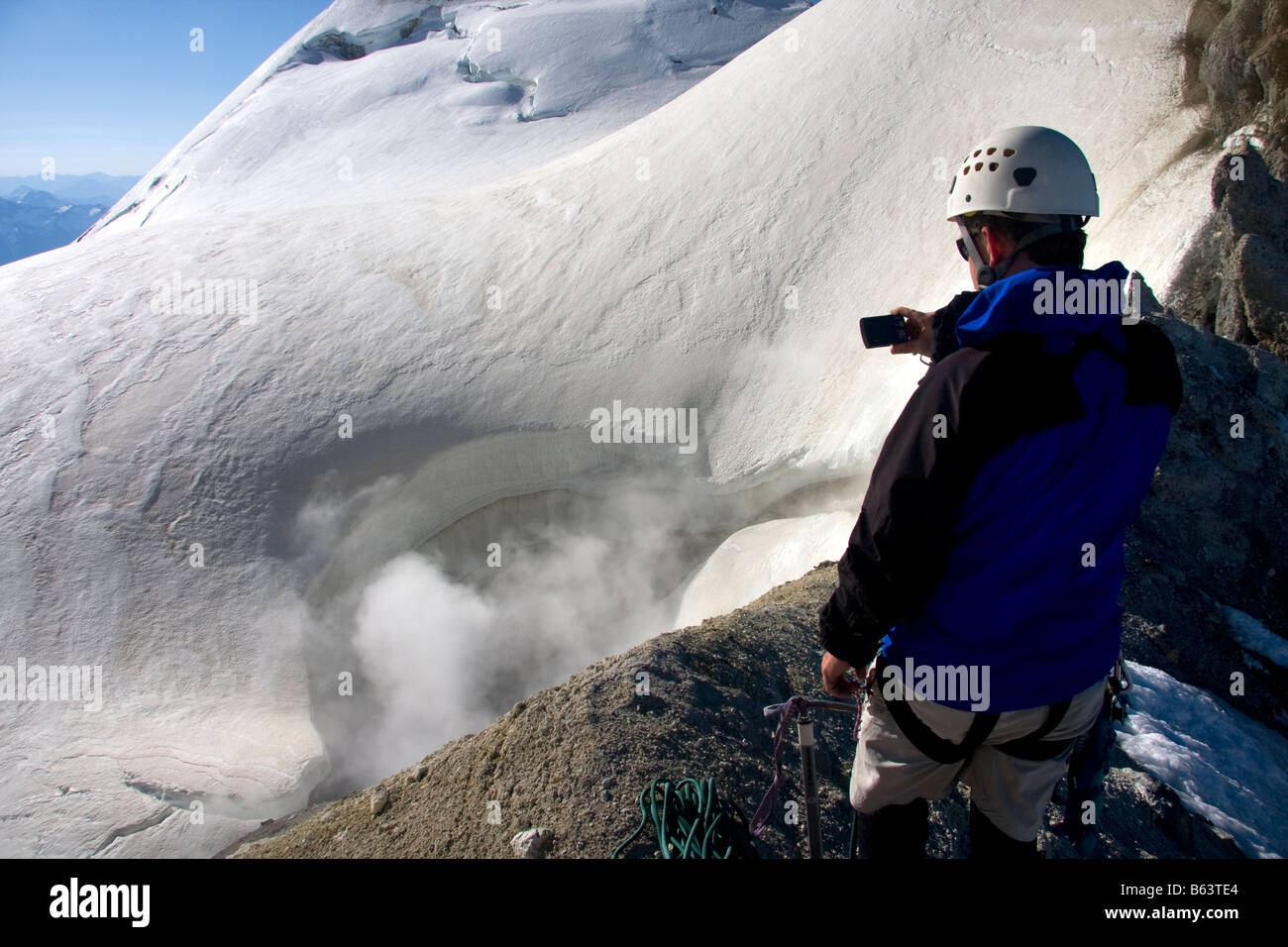 A climber photographs the steam erupting from the summit crater of Mount Baker in the Mount Baker Wilderness North Cascades Wash Stock Photo