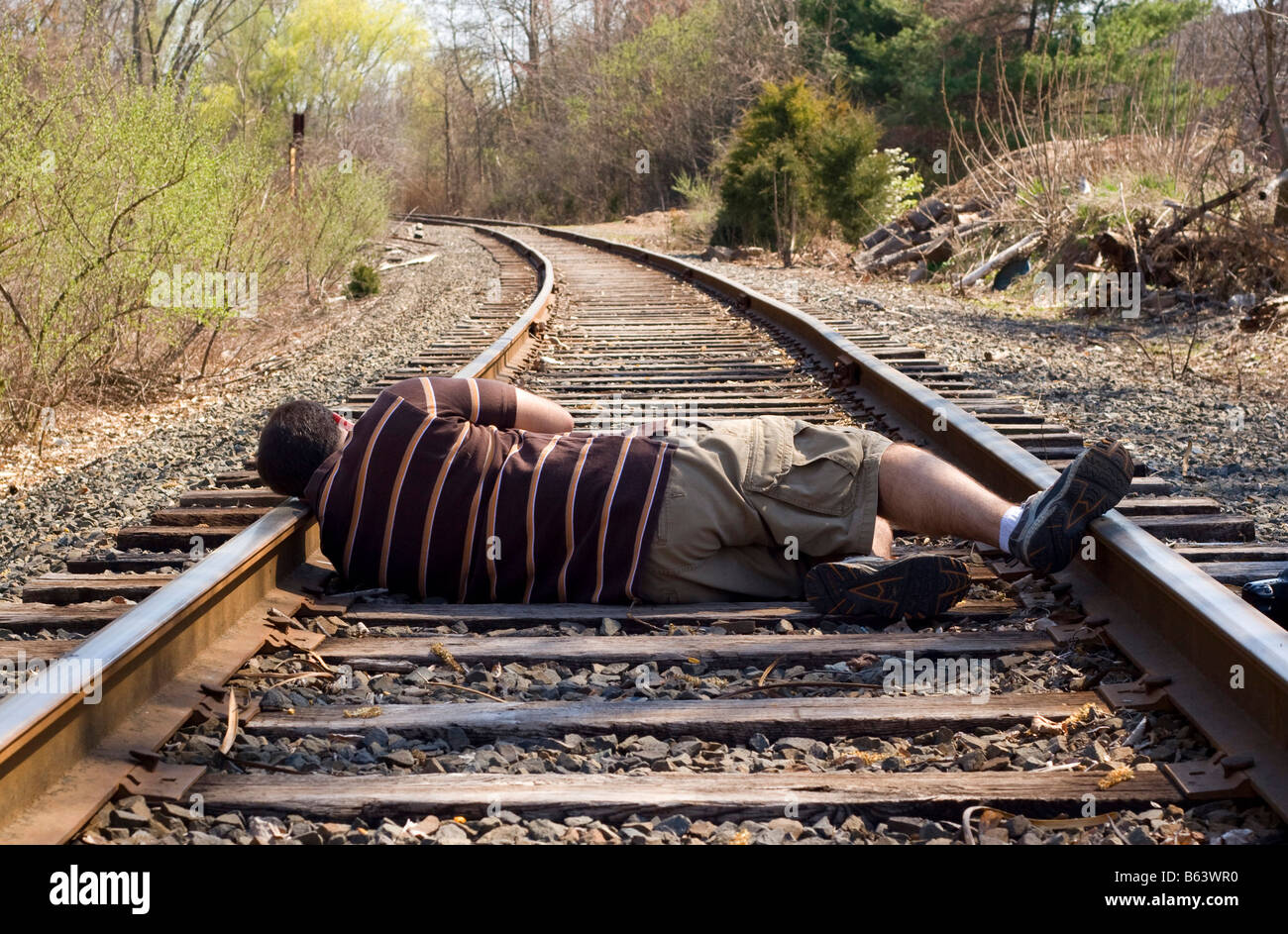 A man laying on the railroad tracks Not exactly the smartest thing to do Stock Photo