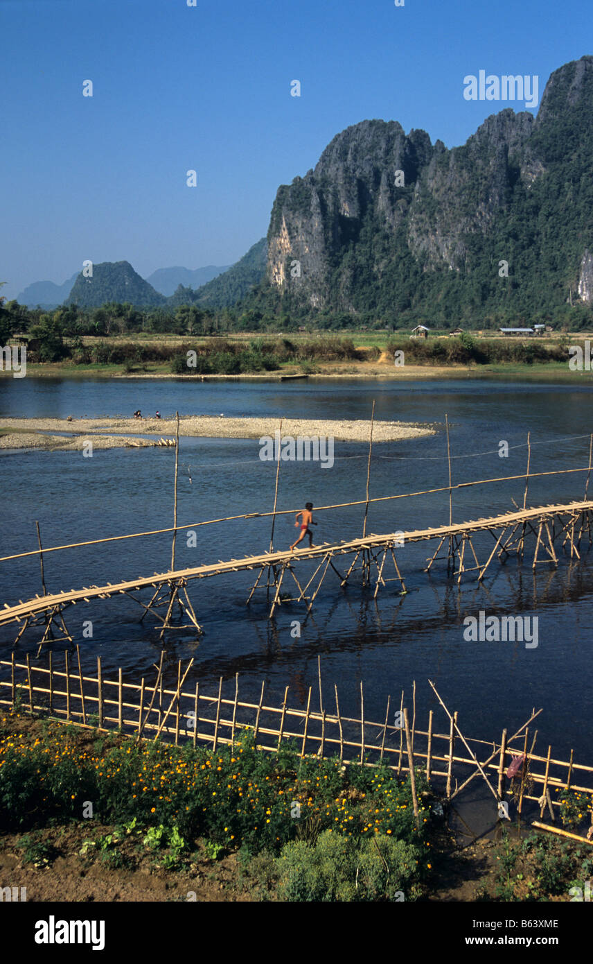 Bamboo bridge across River Song, a Mekong tributary, at Vang Viang, Laos with limestone karst hills in background. Stock Photo