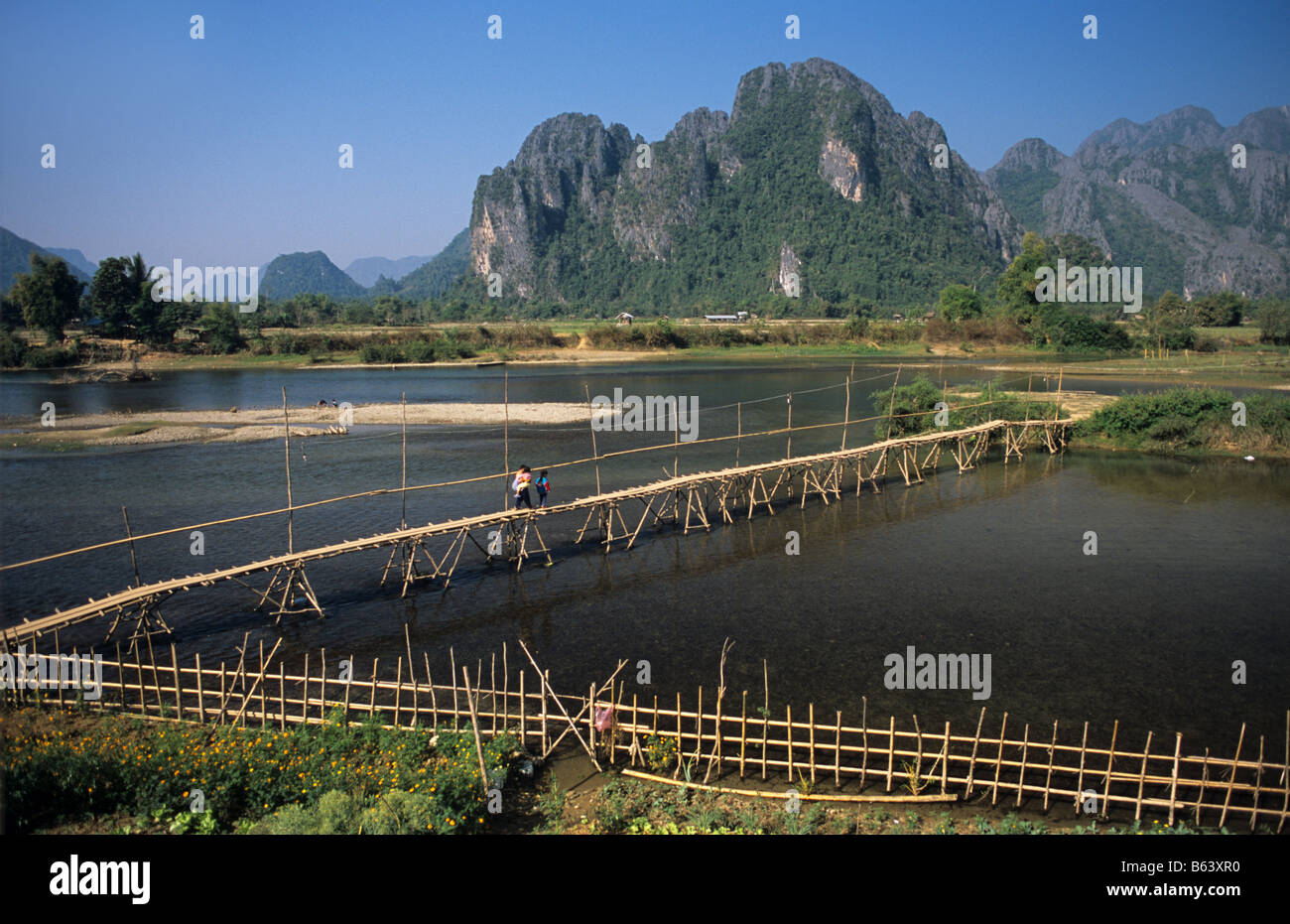 Bamboo bridge across River Song, a Mekong tributary, at Vang Vieng, Laos with limestone karst hills in background. Stock Photo