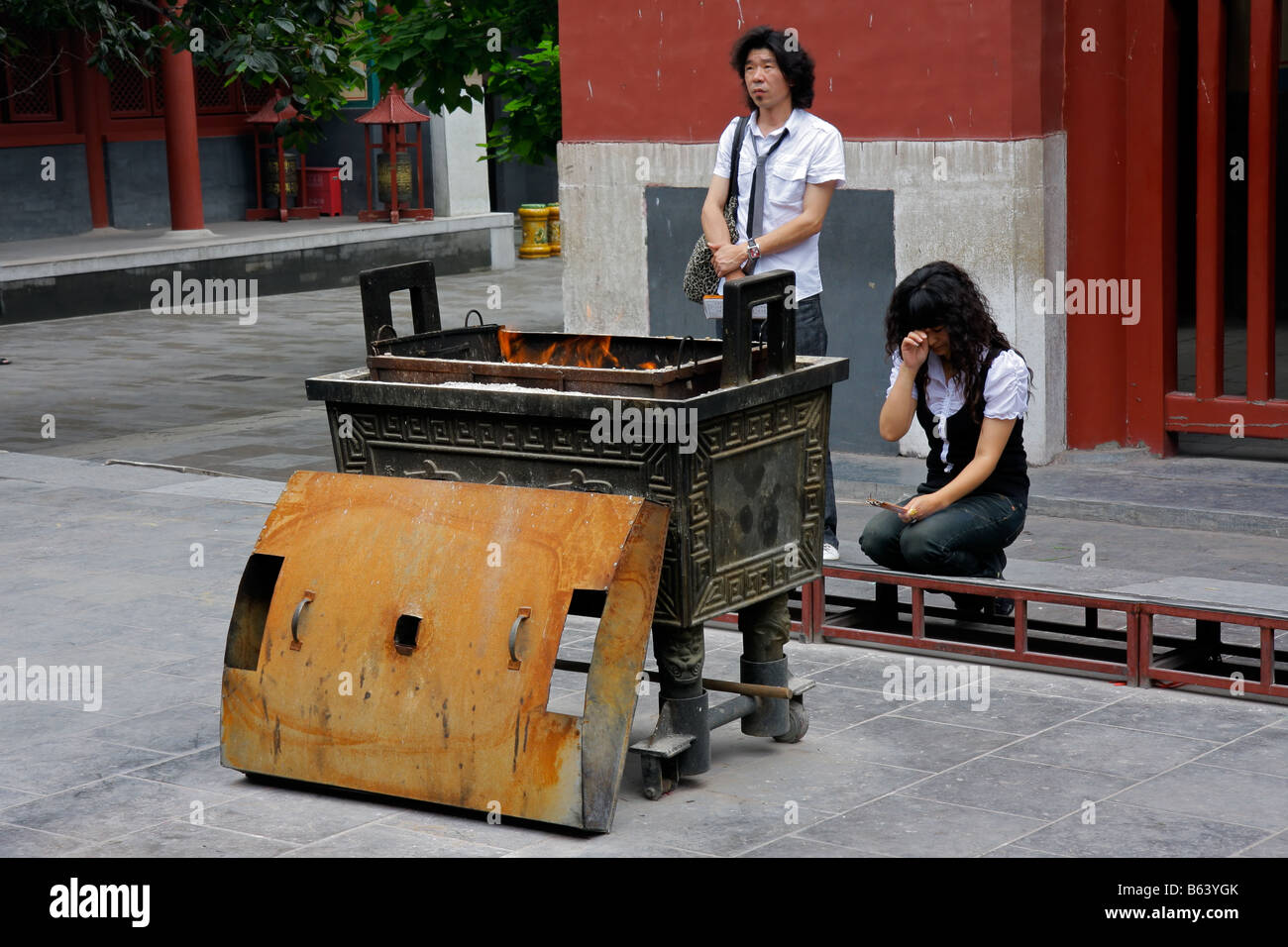 Chinese man and woman in religious offering, burning incense sticks in