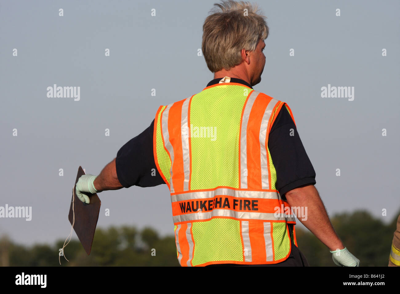 An EMS personnel pointing with a clipboard at a scene of a mass