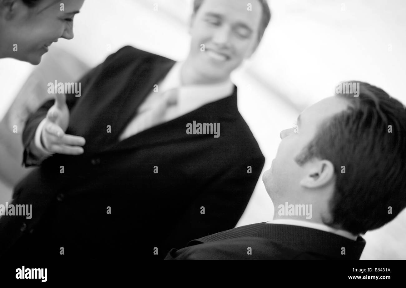 businesspeople in suits standing discussing with each other and smiling Stock Photo
