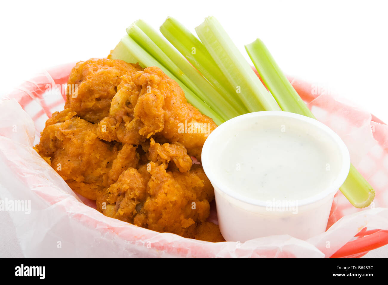 Closeup view of a basket of buffalo chicken wings with celery and ranch