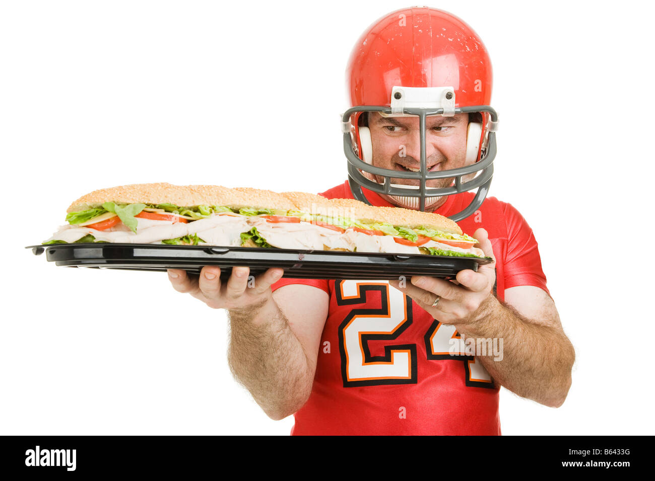 Football player hungrily looking at a giant submarine sandwich Isolated on white Stock Photo