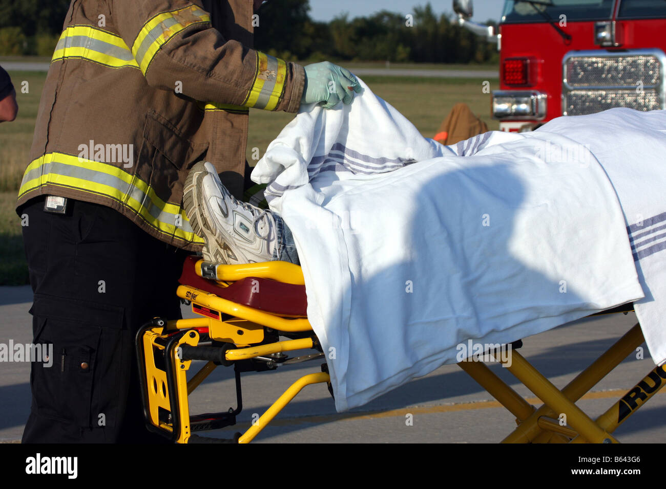 A paramedic raising the blanket on a patient to check on the injury