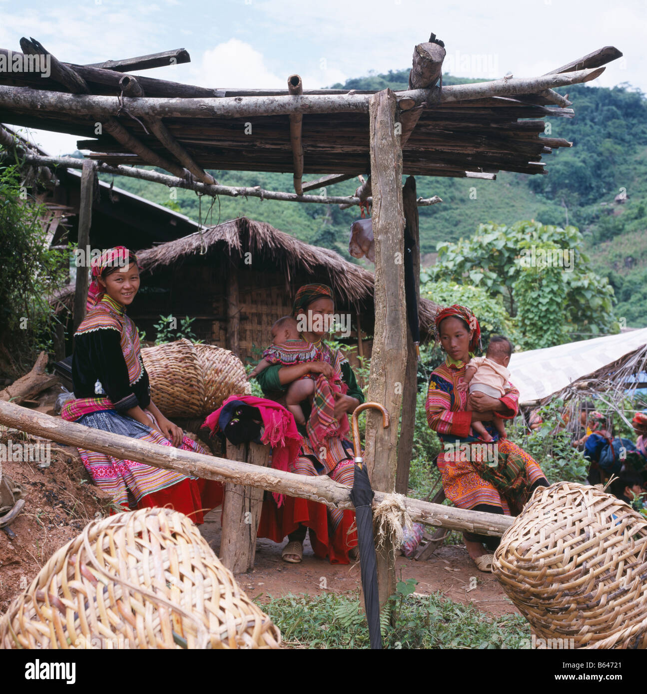 People sit under bamboo shelter two of them holding babies at a north Vietnamese market. Vietnam. Licenced. Chris Kewsih Stock Photo