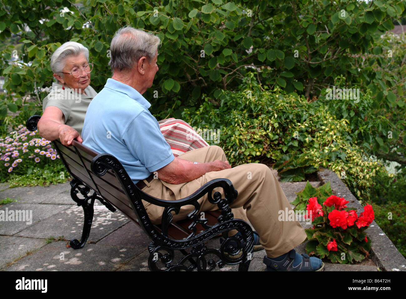 Elderly couple sitting on a bench in a garden Stock Photo - Alamy