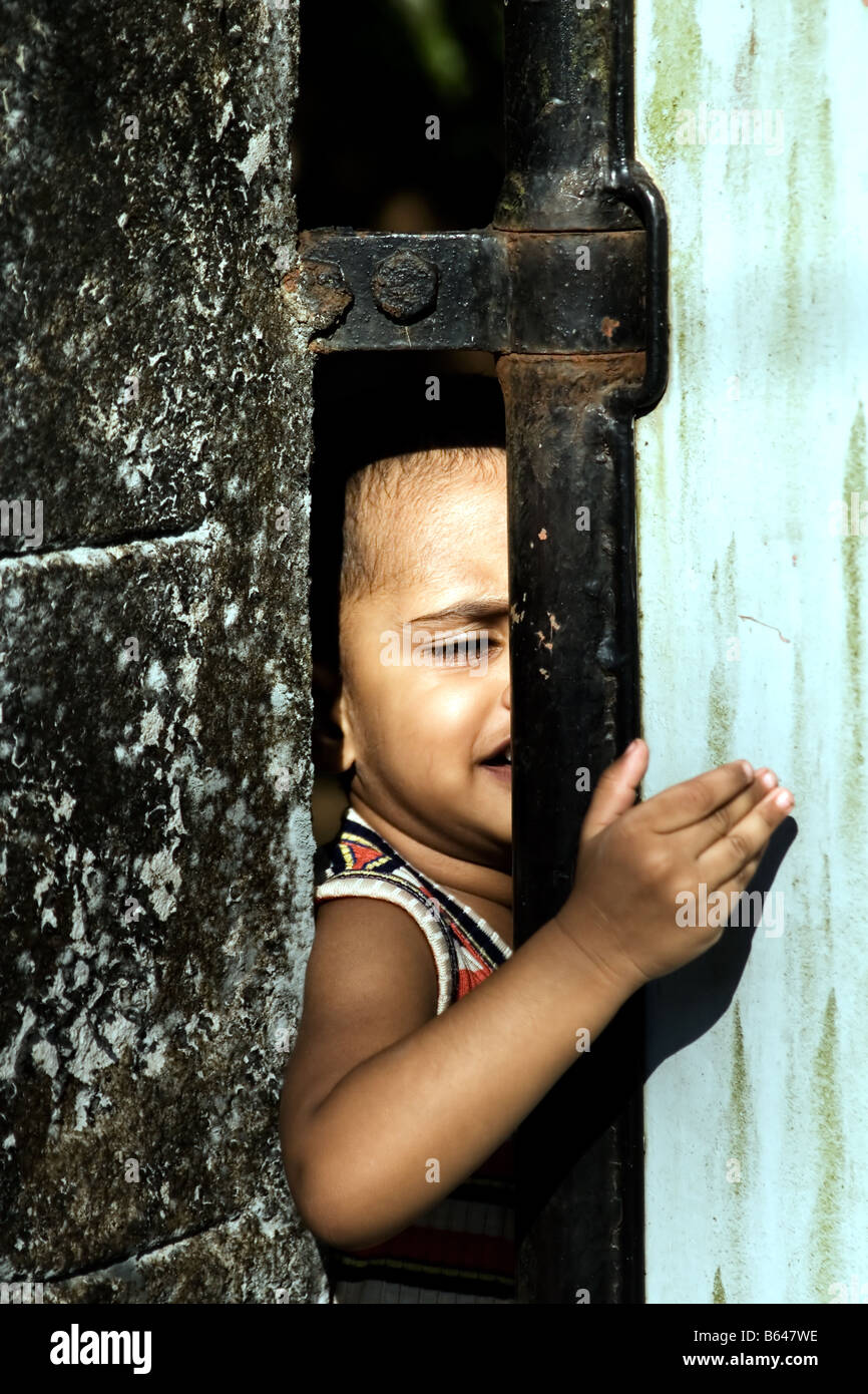 A preschool boy behind a closed gate calling for help Stock Photo