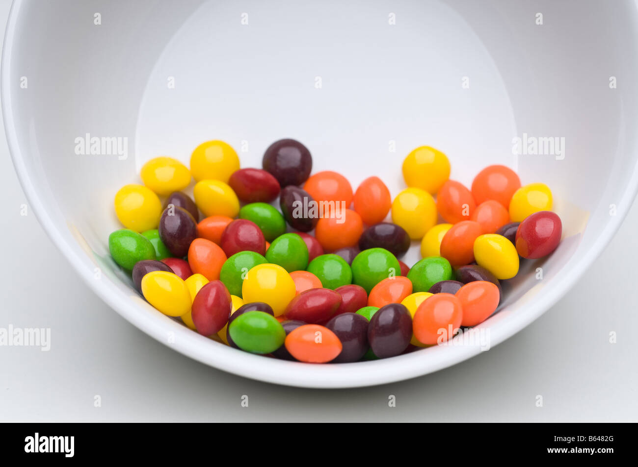 Colurful candies in a tilted white bowl Stock Photo
