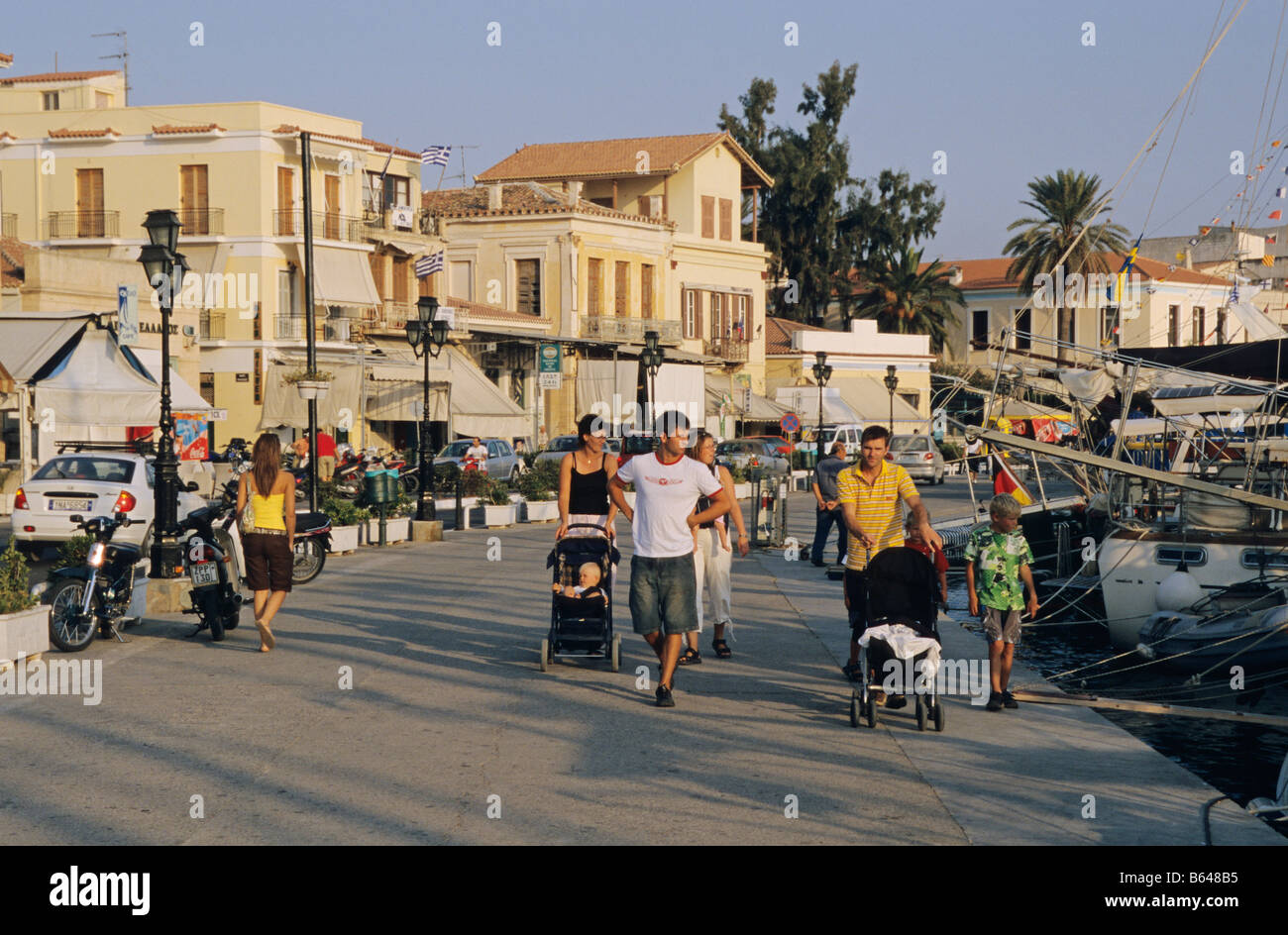 Families walking along the cafe lined waterfront, Aegina Town on the island of Aegina, Greece Stock Photo