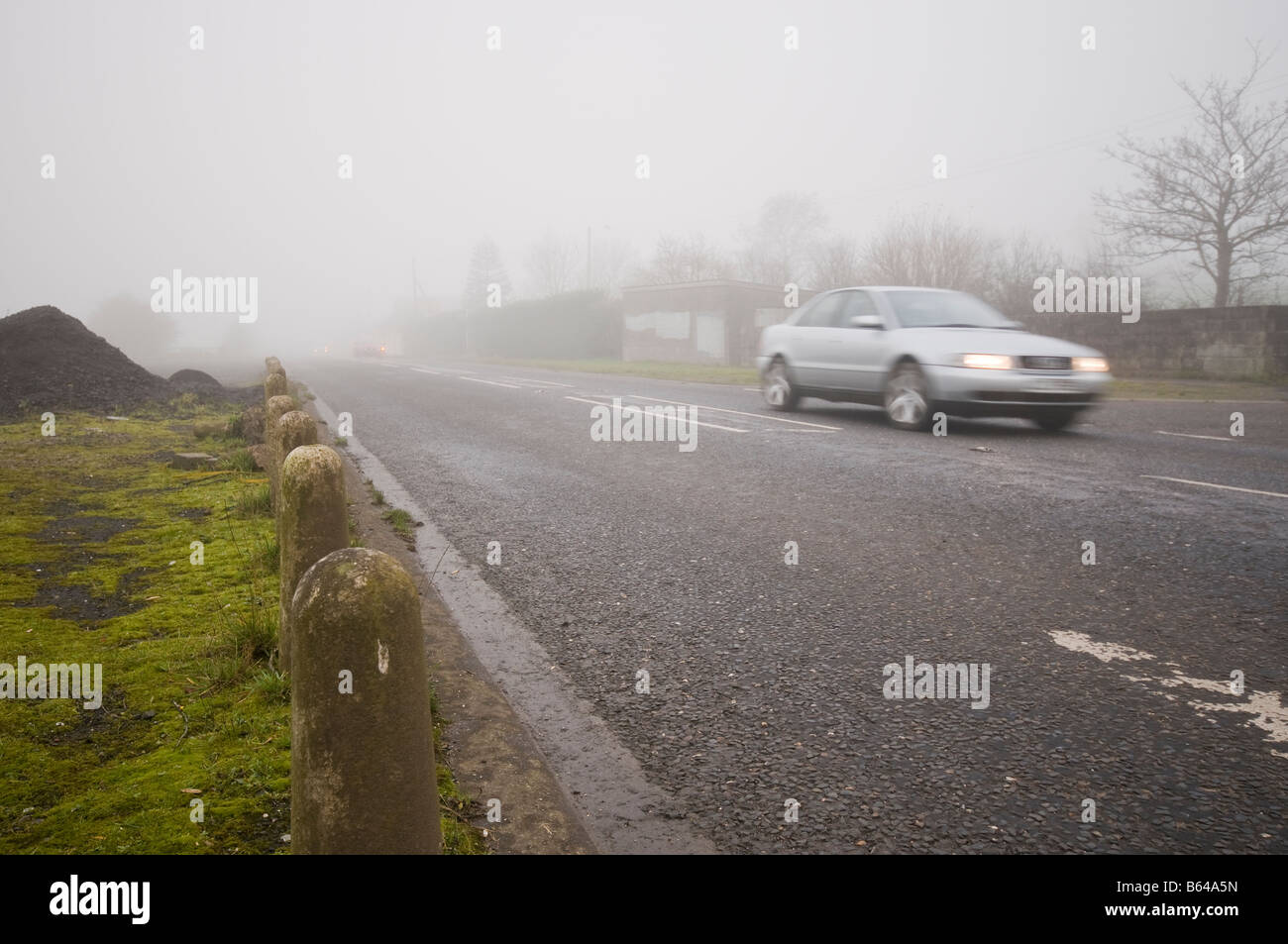 Cars speeding along a country road in fog/mist with low visibility ...