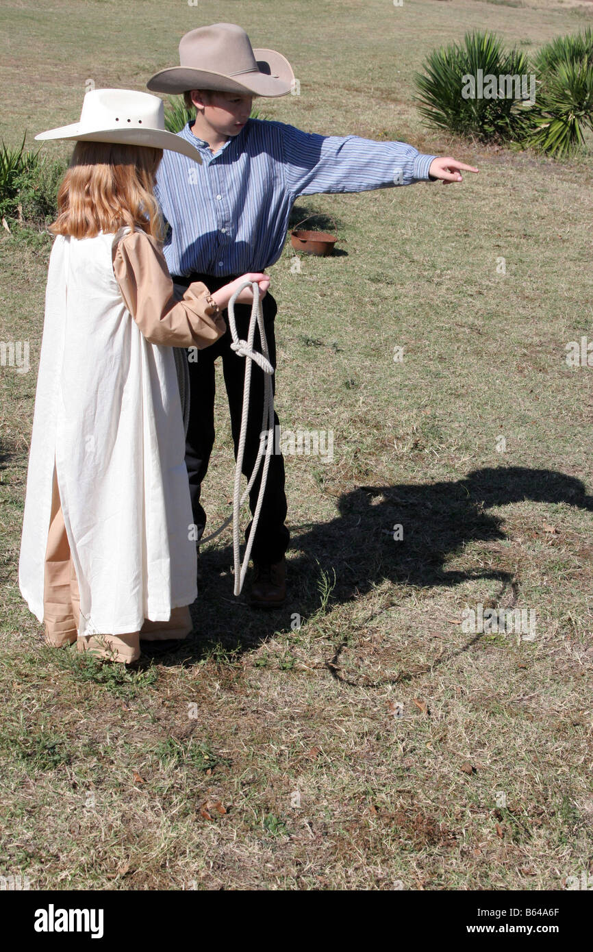 A young cowboy is teaching a young girl how to throw a rope Stock Photo