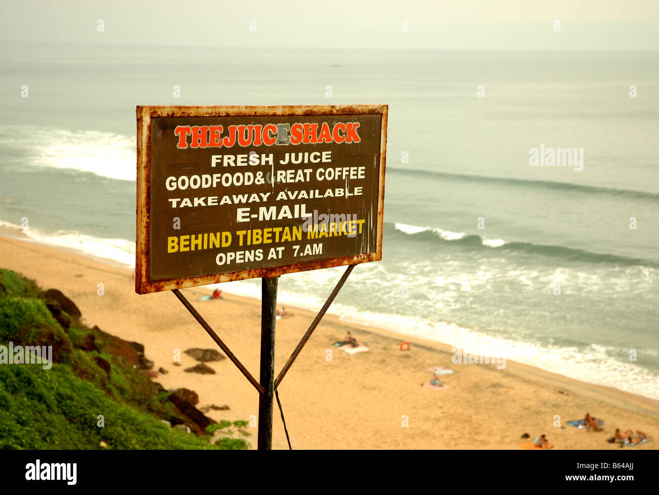The Juice Shack wooden sign and the beach and cliff face at Varkala