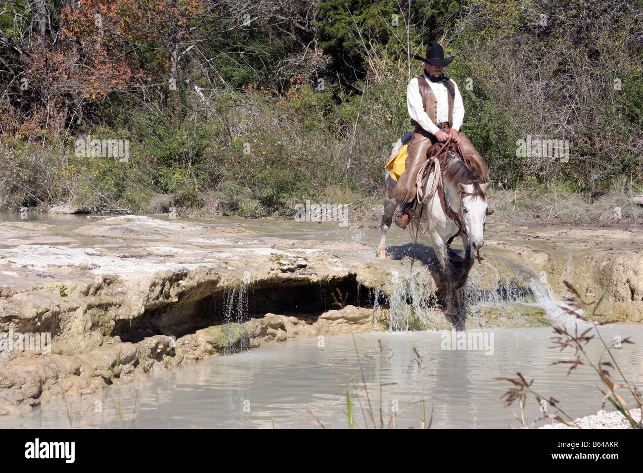 A cowboy and horse crossing a stream in Texas Stock Photo