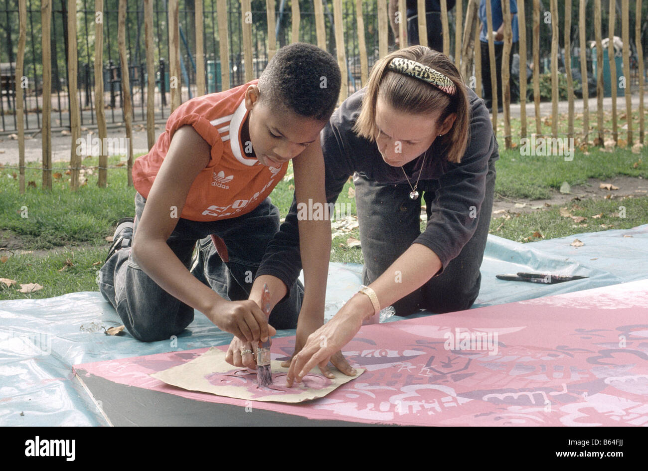 primary school boy painting a mural with the help of a teacher Stock Photo