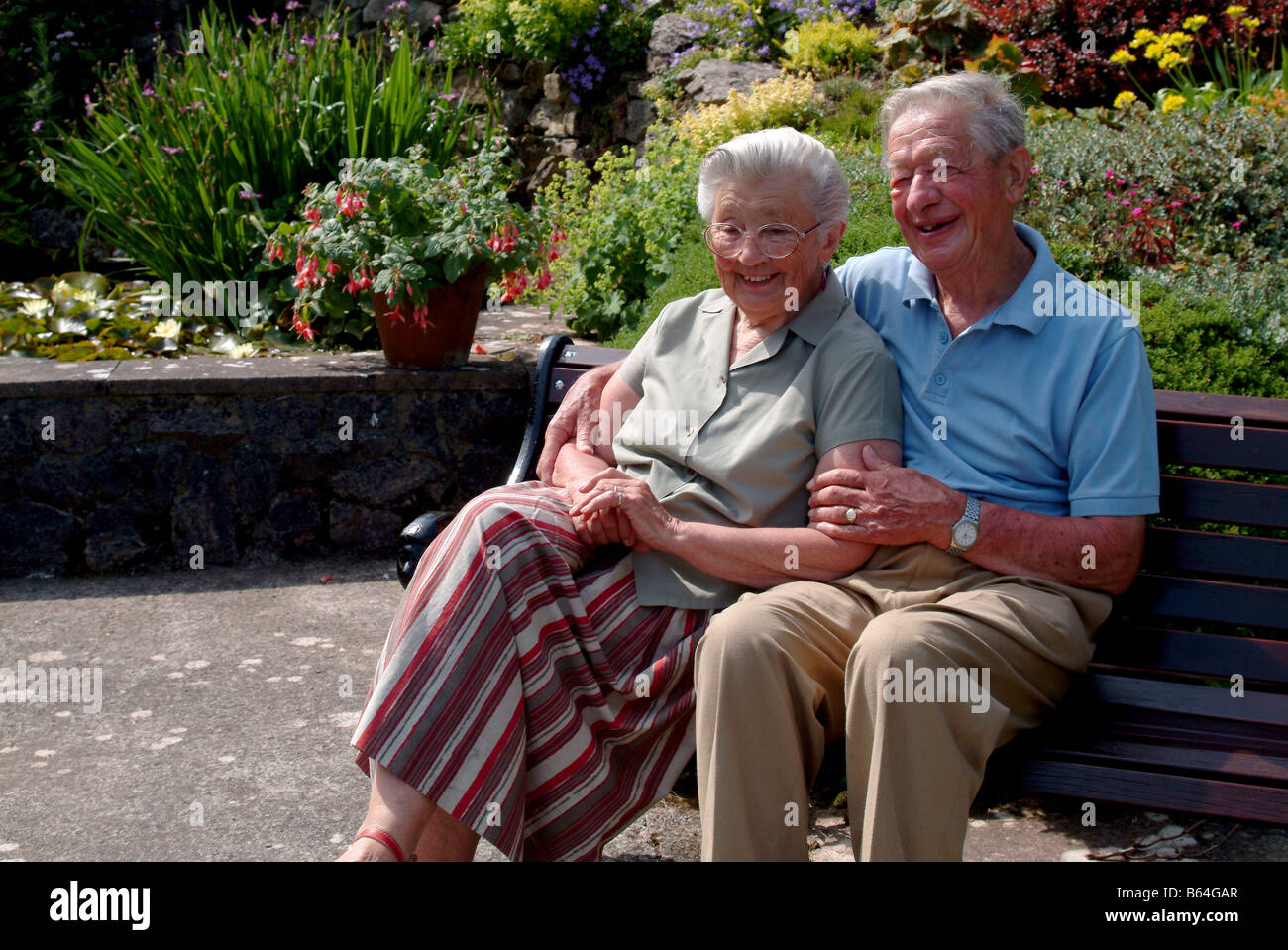 Elderly couple sitting on a bench together Stock Photo - Alamy