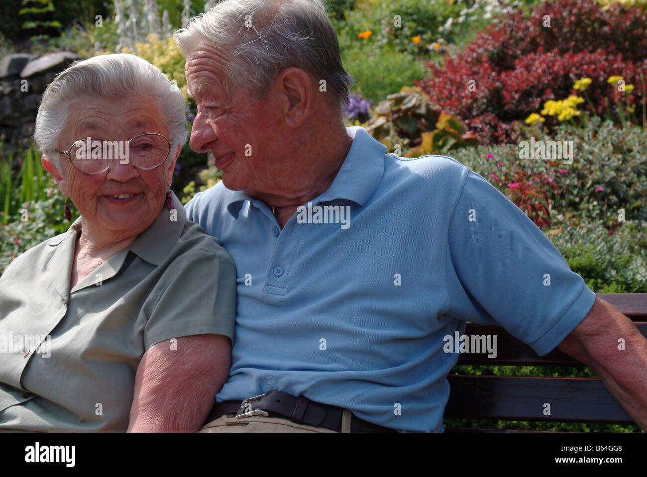 Elderly couple sitting on a bench together Stock Photo - Alamy
