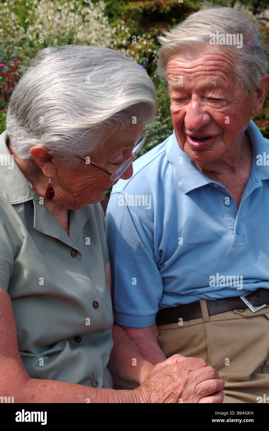 Elderly couple sitting and holding hands Stock Photo