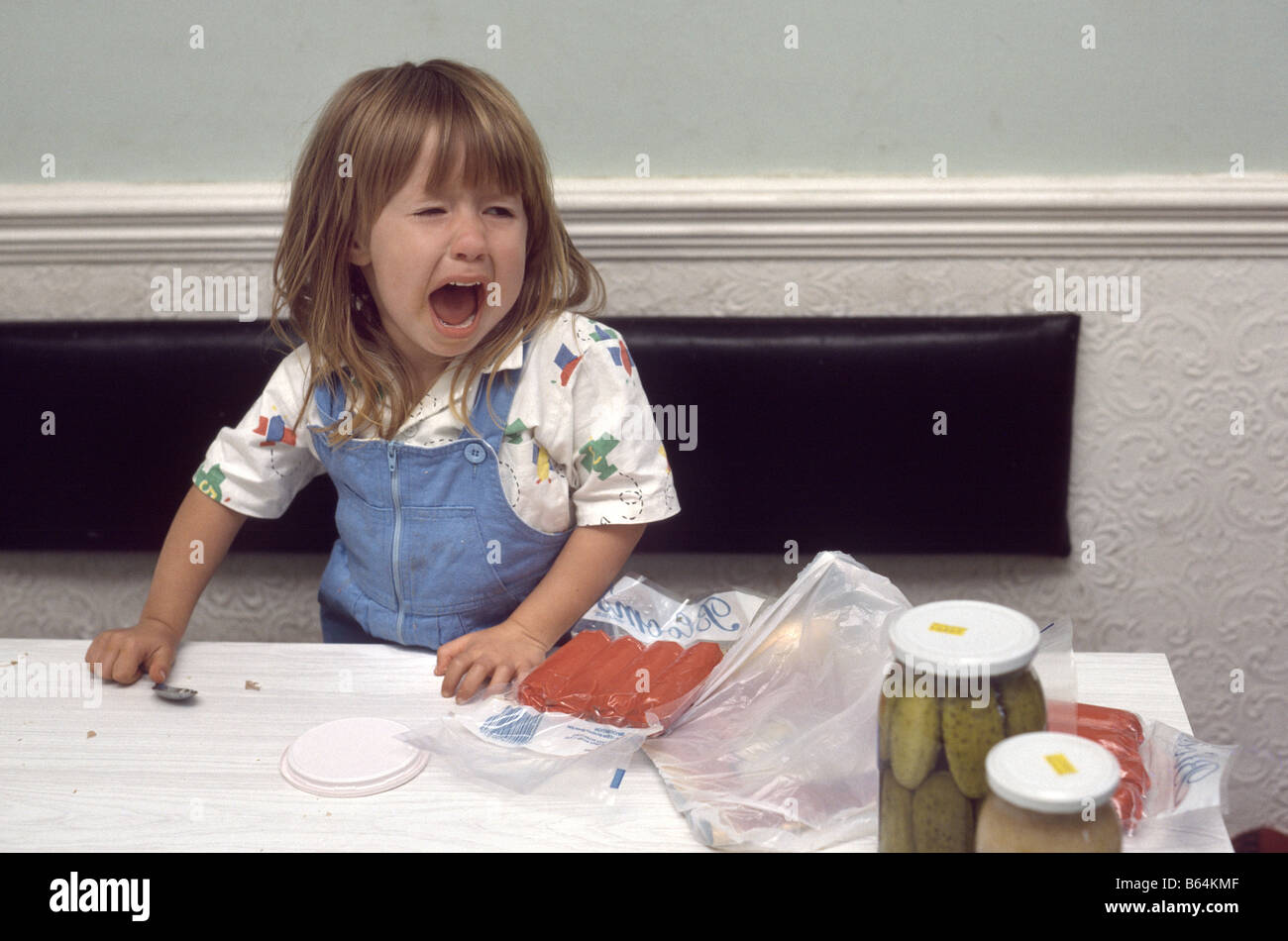 young girl crying at the kitchen table Stock Photo
