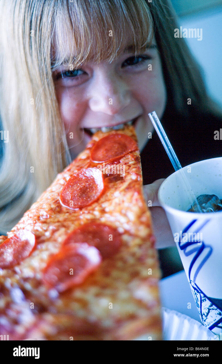 Young girl, closeup of face, eating a slice of pizza, drinking soda thru a straw, smiling, Miami Stock Photo
