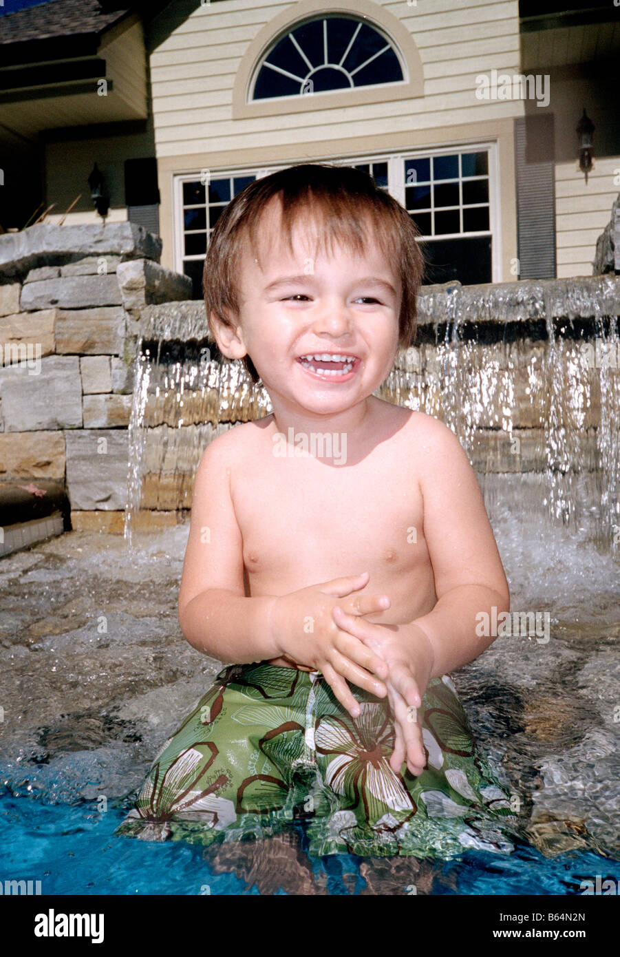 1.5 year old Eurasian boy in an outdoor swimming pool with waterfall