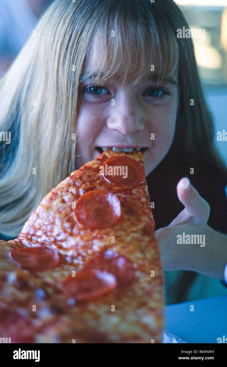 Young girl, closeup of face, eating a slice of pizza, smiling, Miami Stock Photo