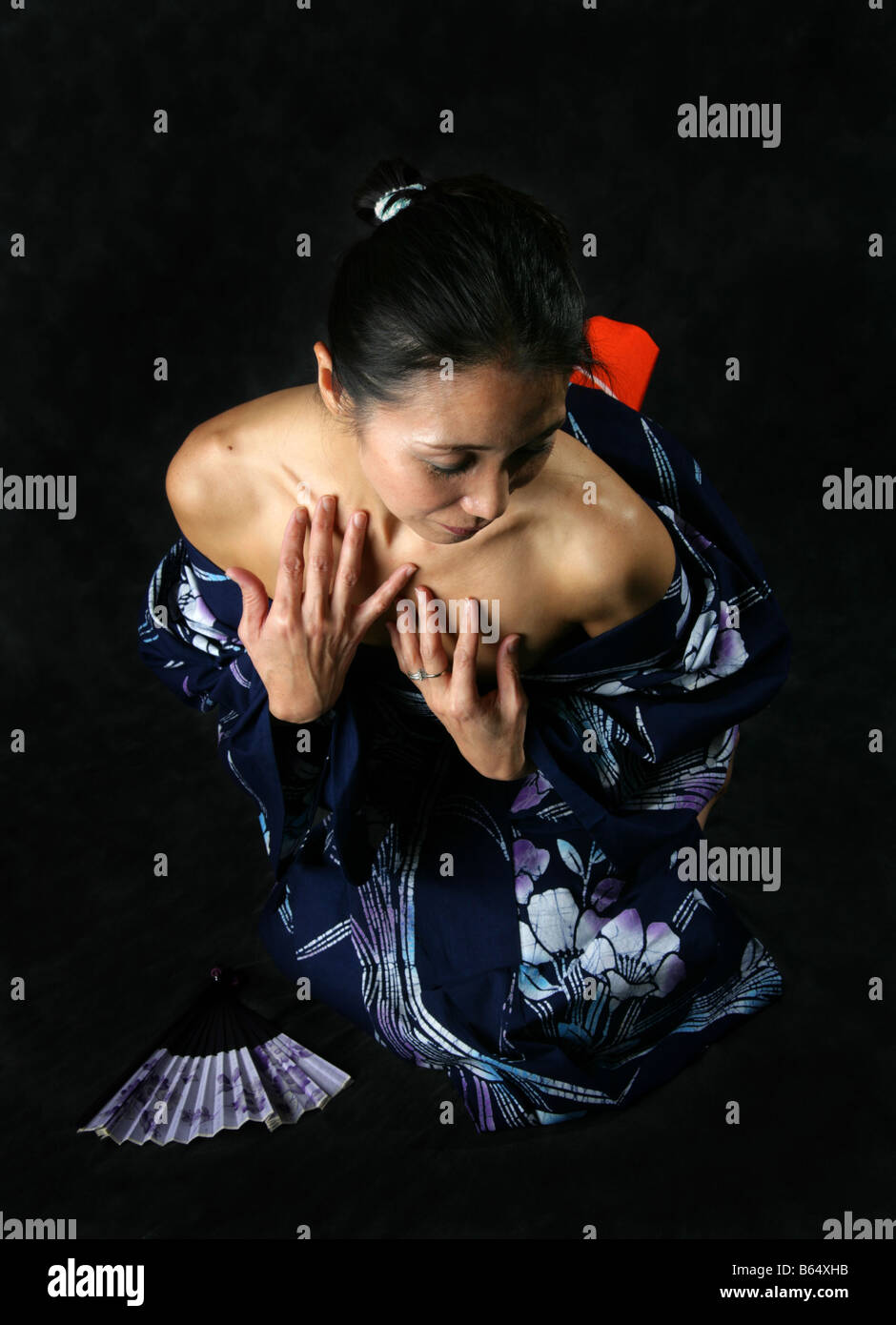 Japanese Woman in a Blue Kimono, Kneeling in a Submissive Position Stock Photo