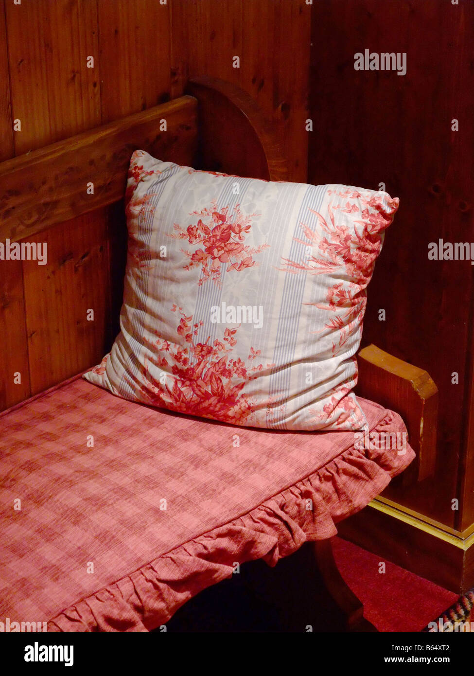 Red pillow kept on a wooden bench Stock Photo