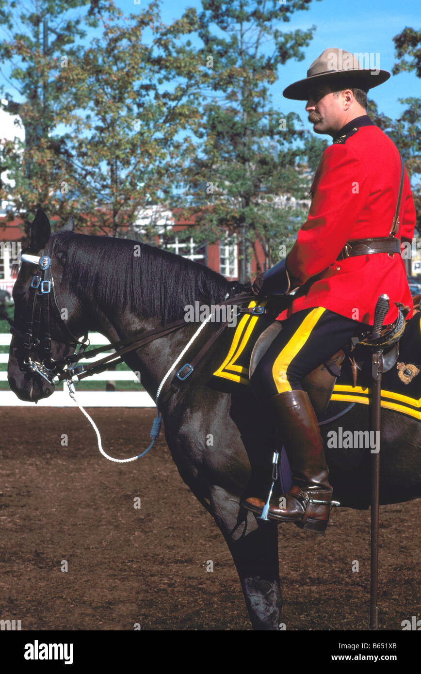 A Canadian Mountie (RCMP) Royal Canadian Mounted Police Officer riding on Horseback and wearing Traditional Red Serge Uniform Stock Photo