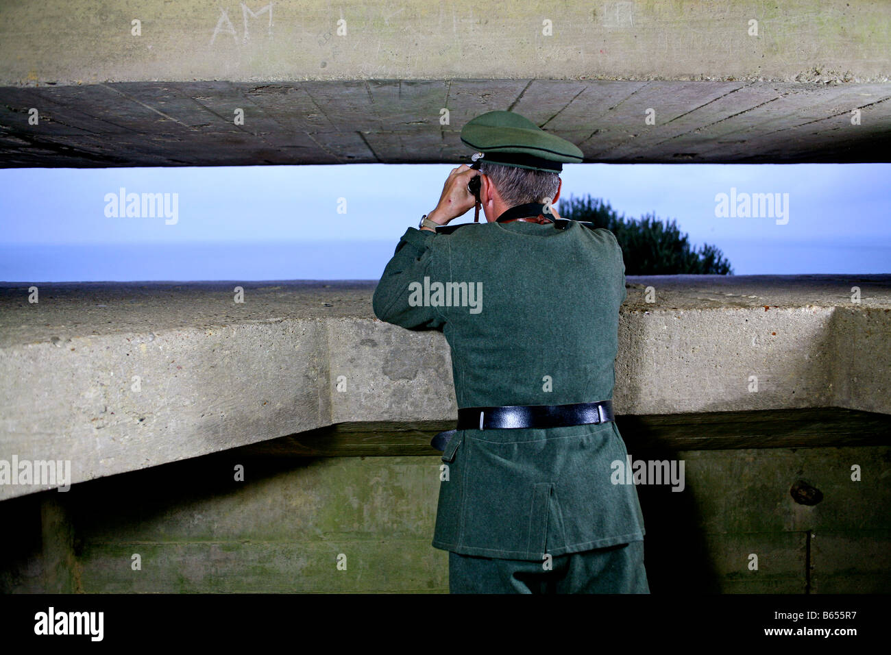 An actor dressed as a German officer looking out over the English Channel,from a German D Day bunker in Normandy France Stock Photo