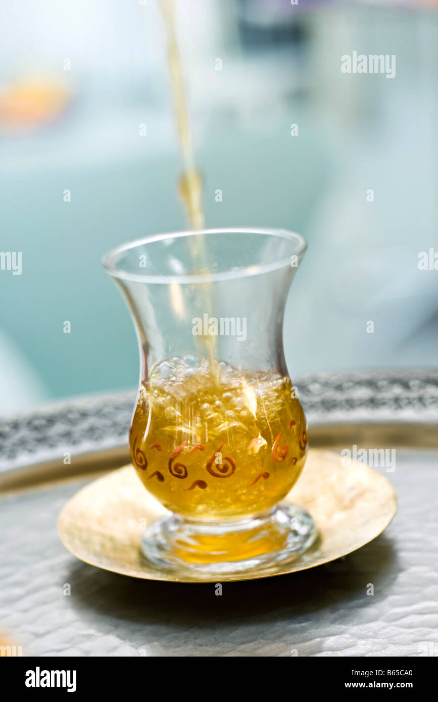 Tea pouring into glass cup placed on saucer Stock Photo