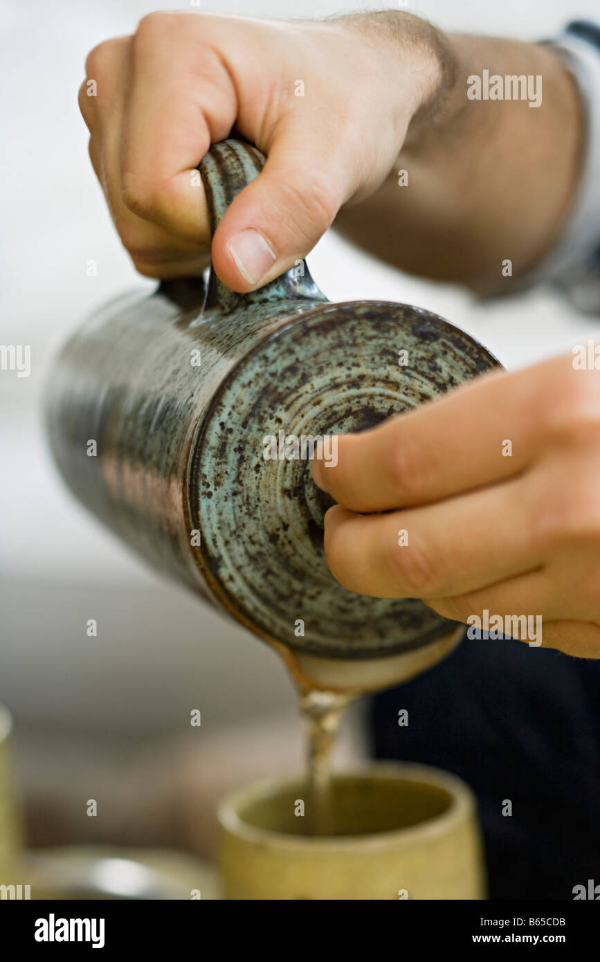 Hands pouring tea into cup Stock Photo