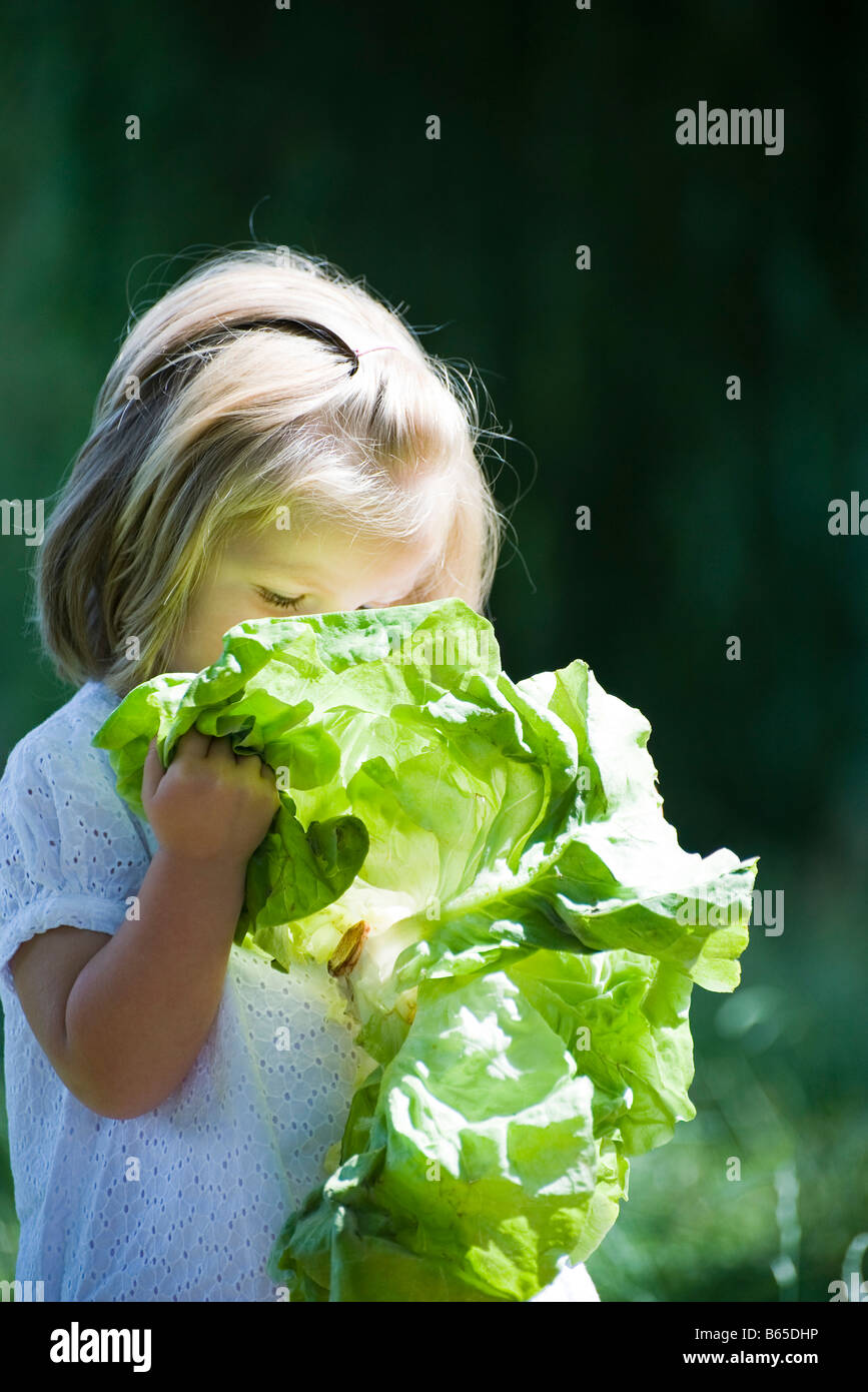 Little girl holding up chard to her face Stock Photo
