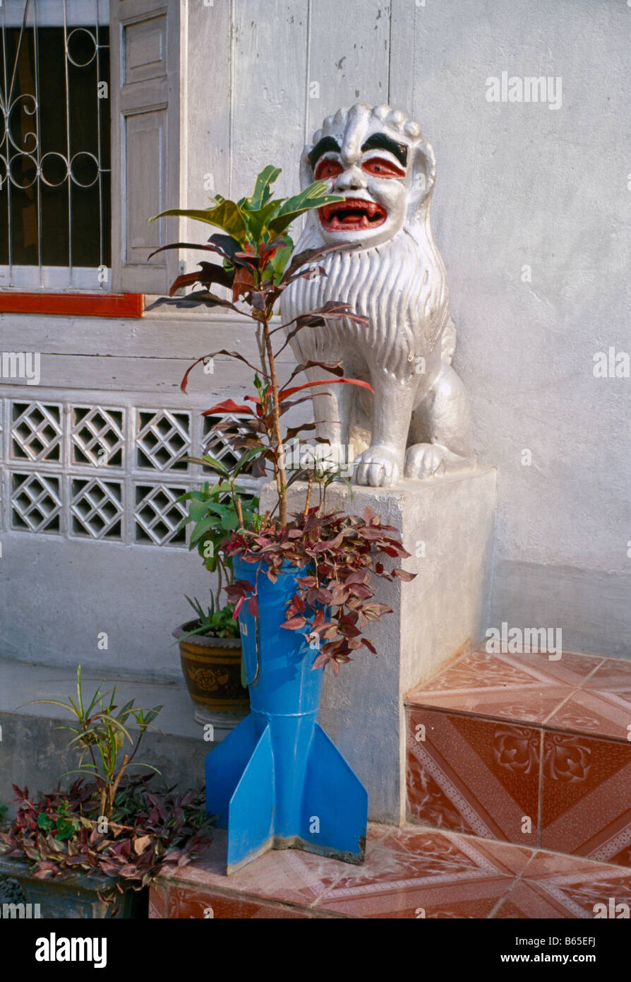 old unexploded bomb from the vietnam war recycled as a flower pot beside the entrance of a temple in Luang Prabang Laos Stock Photo