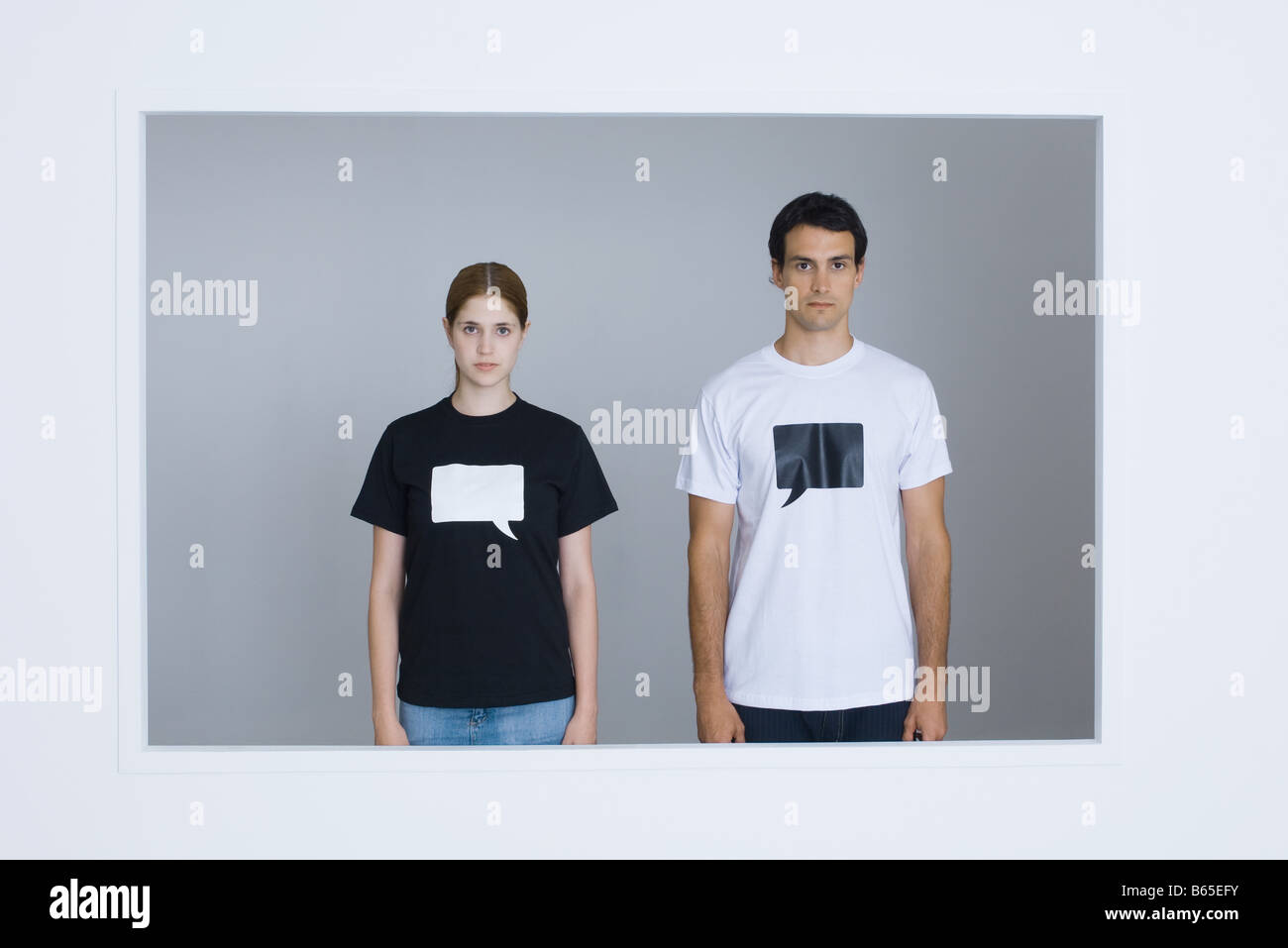 Young  man and young woman wearing tee-shirts printed with blank word bubbles, looking at camera Stock Photo