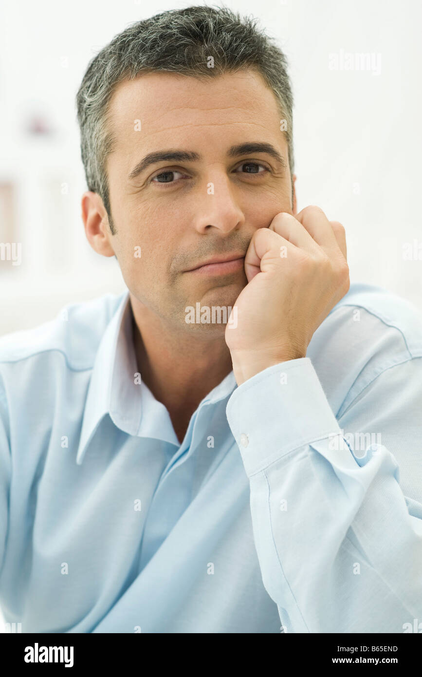 Man holding head, looking at camera, portrait Stock Photo