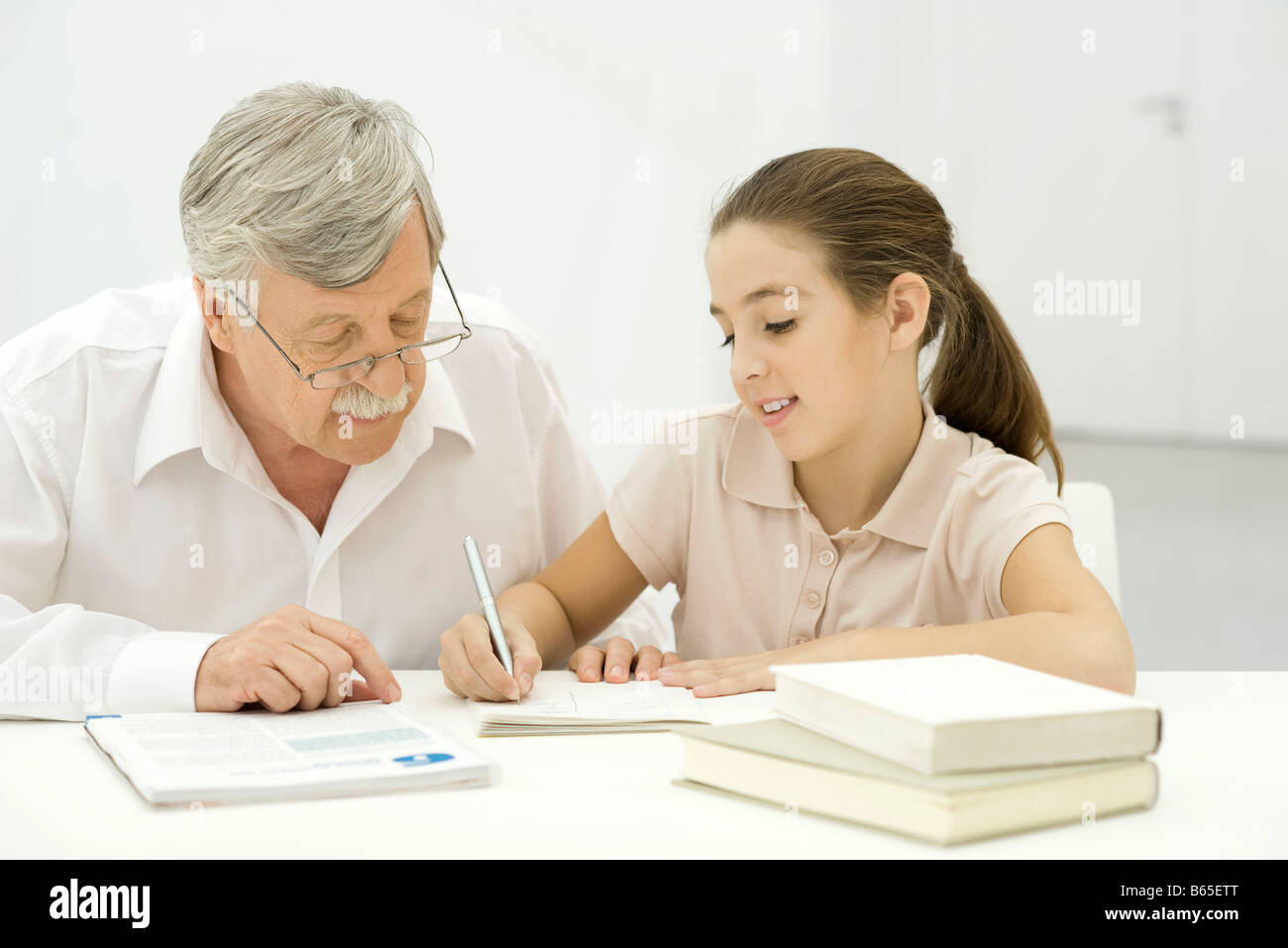 Grandfather helping granddaughter with homework Stock Photo