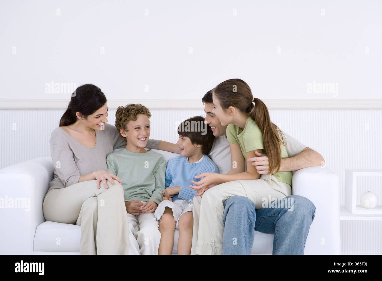 Family with three children sitting together on sofa, talking Stock Photo