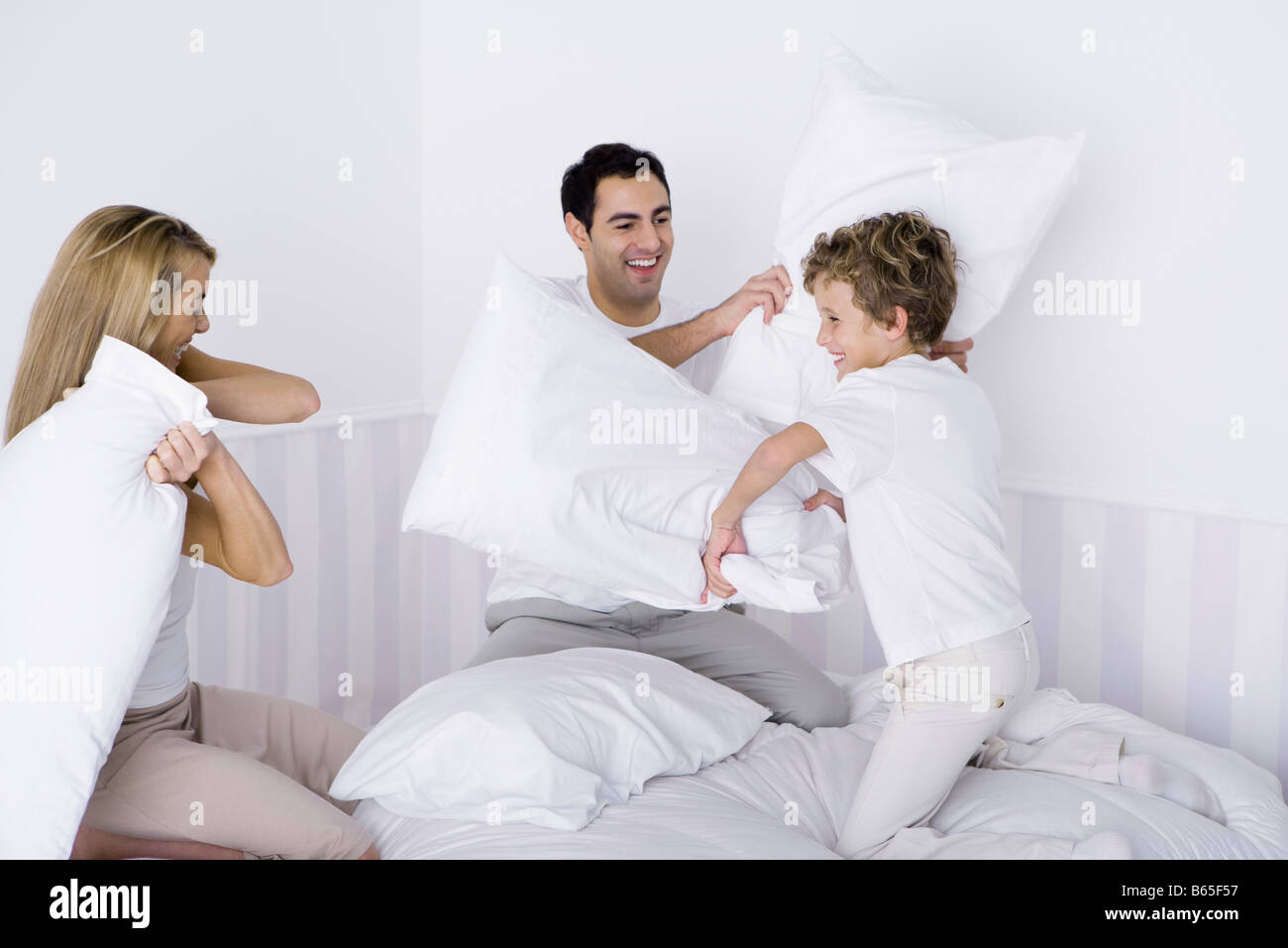Family having pillow fight on bed Stock Photo
