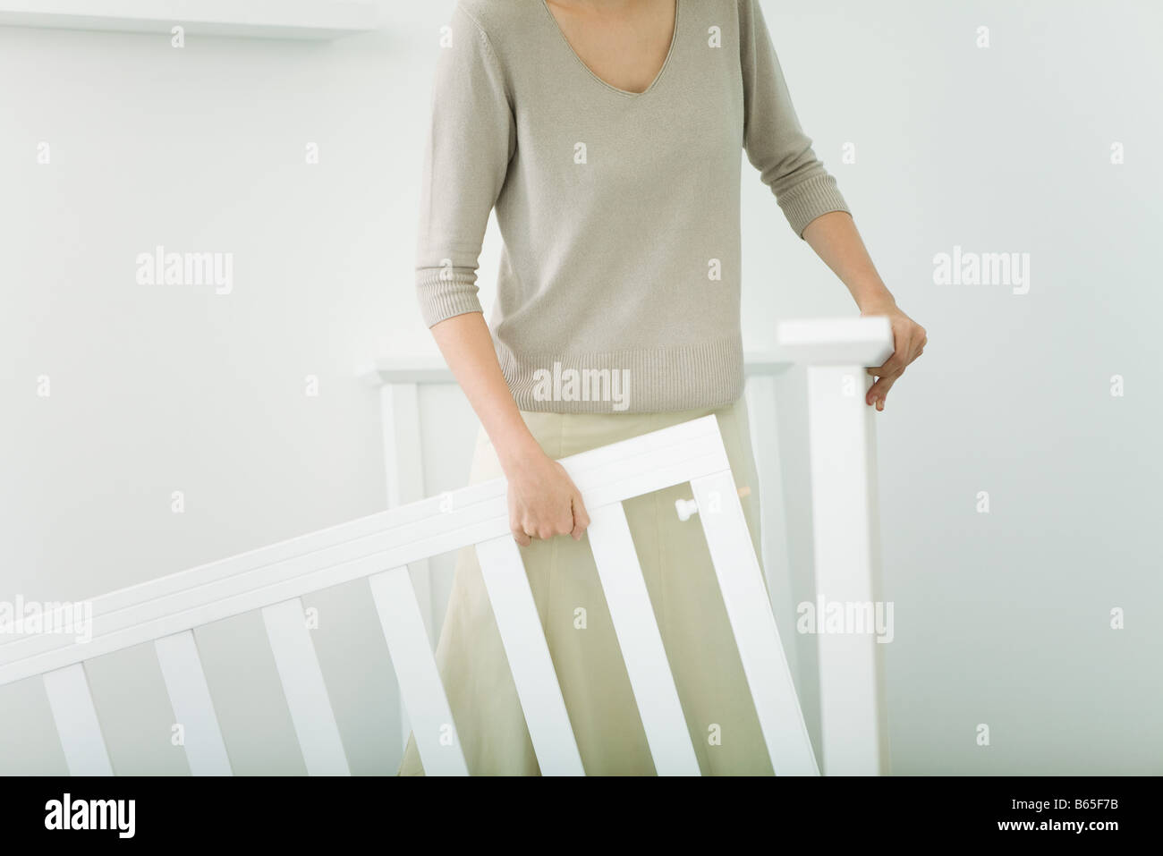 Woman assembling crib in nursery, cropped view Stock Photo