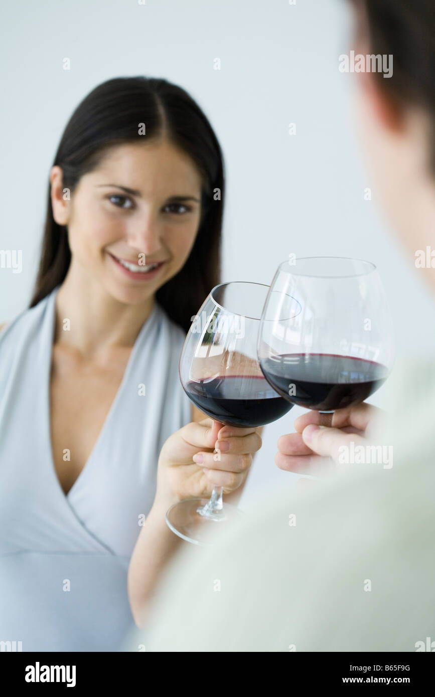 Couple clinking glasses of red wine, woman smiling at camera, cropped view Stock Photo Alamy