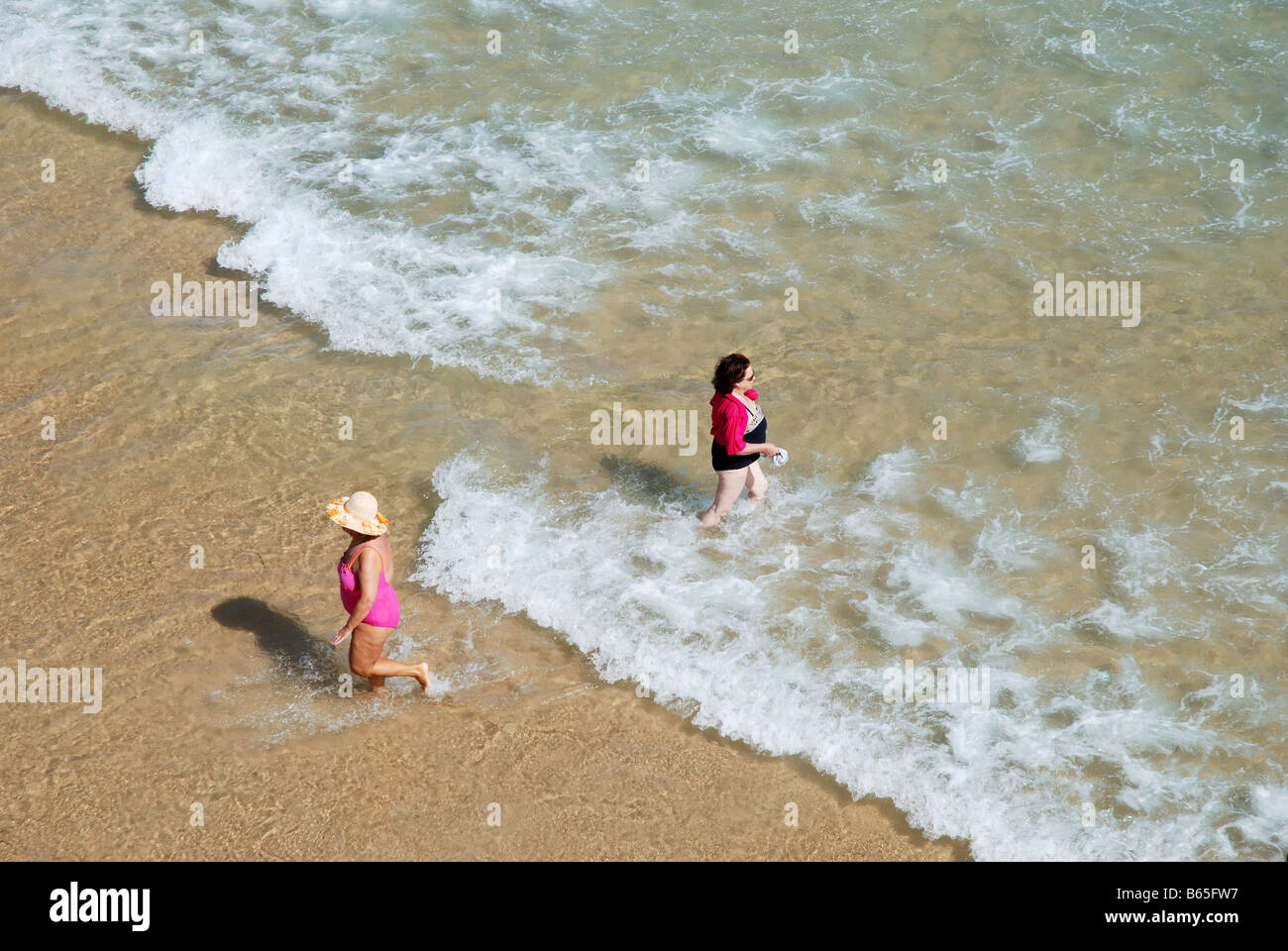 Two mature women walking on the sea shore. El Sardinero beach. Santander. Cantabria province. Spain. Stock Photo